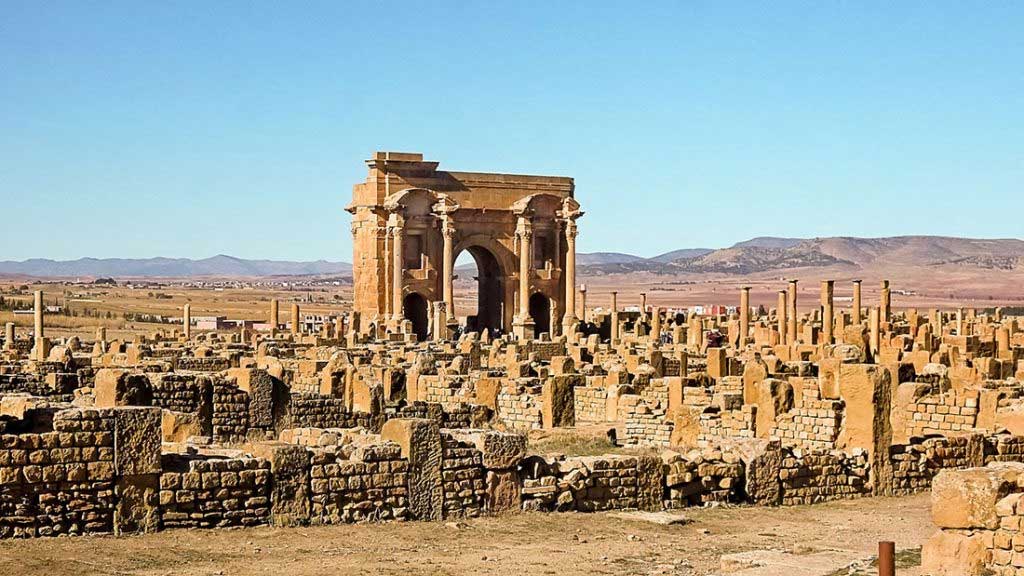 Руины с аркой Траяна на заднем плане, город Тимгад